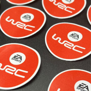 Round orange EA Sports WRC vinyl stickers displayed on a dark surface
